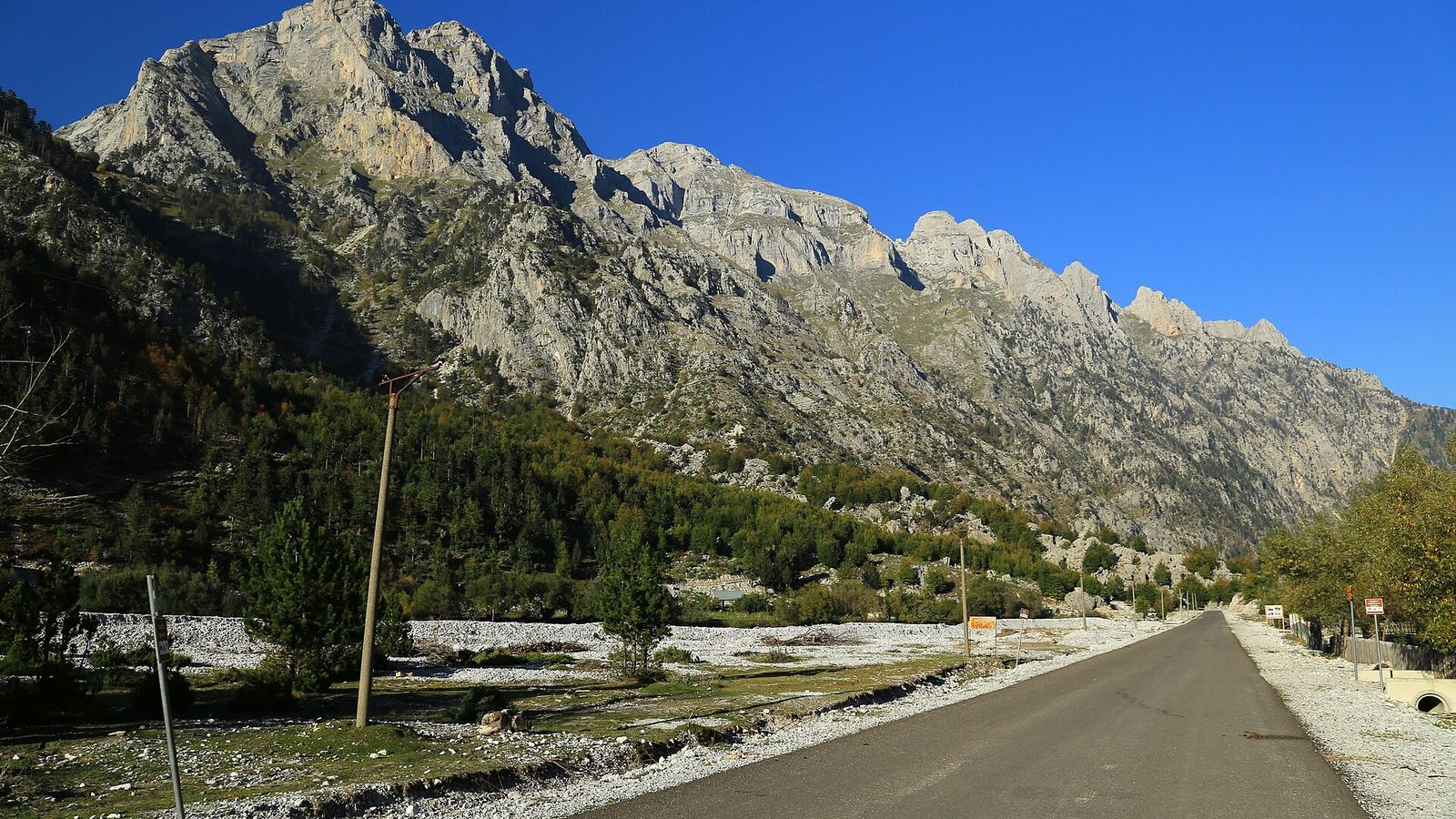 Newly built road under the limestone peaks of the Valbona Valley, Valbone Valley National Park, Albania