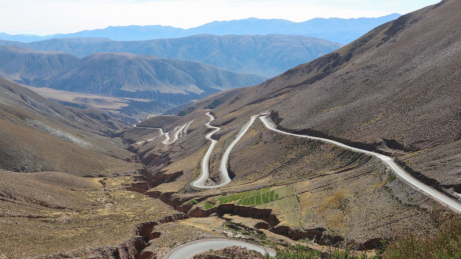 National Route 52 climbing the Cuesta de Lipán hairpins above the Quebrada de Humahuaca, Jujuy, with the coloured Andean ranges behind.