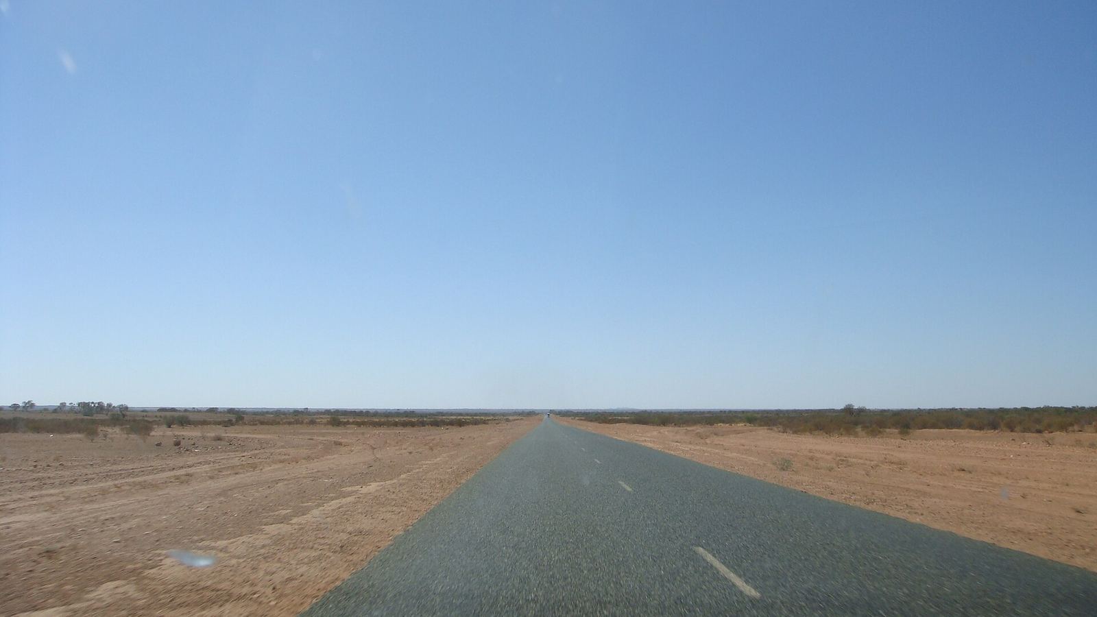 Long straight outback road across red dusty plains under a big sky, Australia