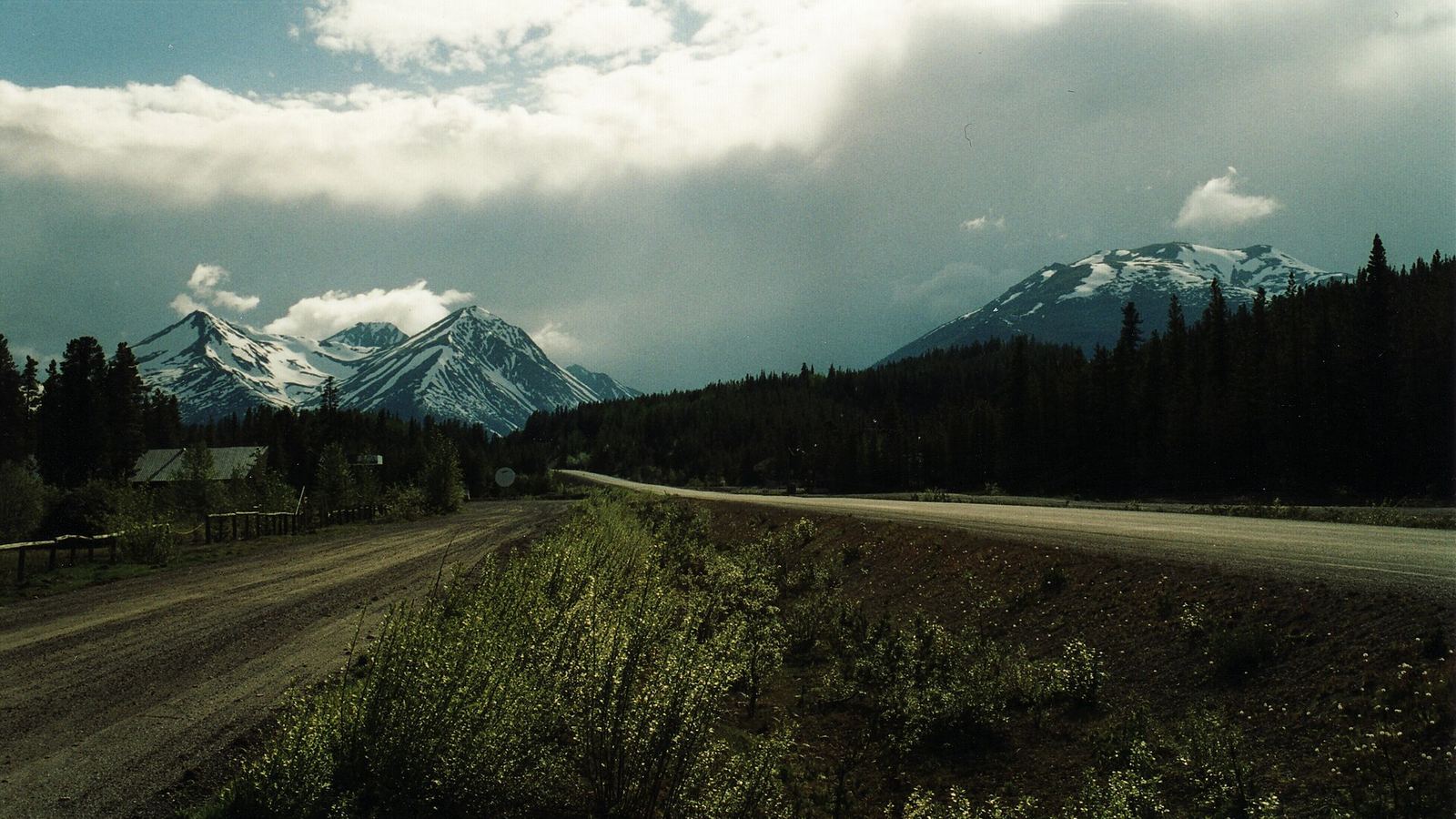 Gravel road and highway toward snow-capped peaks at Jade City on the Cassiar Highway, British Columbia, Canada