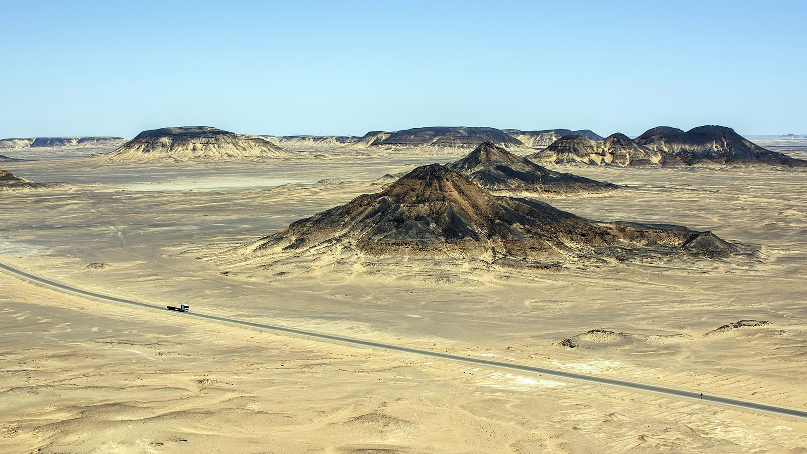 Asphalt road with a lorry crossing the Black Desert, Bahariya Oasis, Western Desert, Egypt