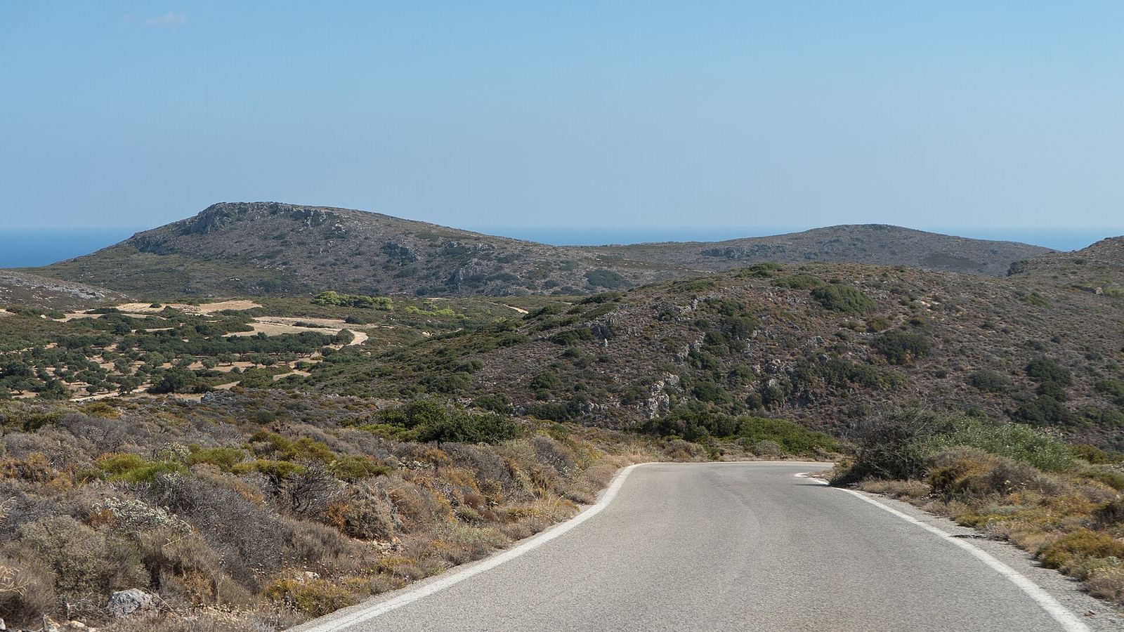 Empty rural road on Kythira island, scrubby hills and the sea beyond