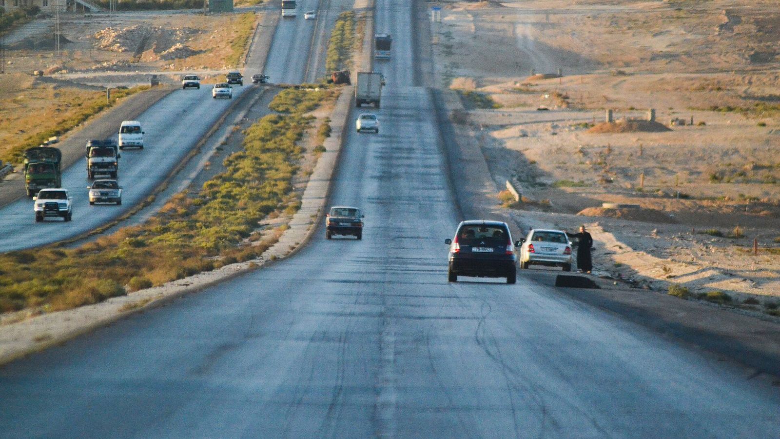 Desert highway towards Amman with trucks and cars