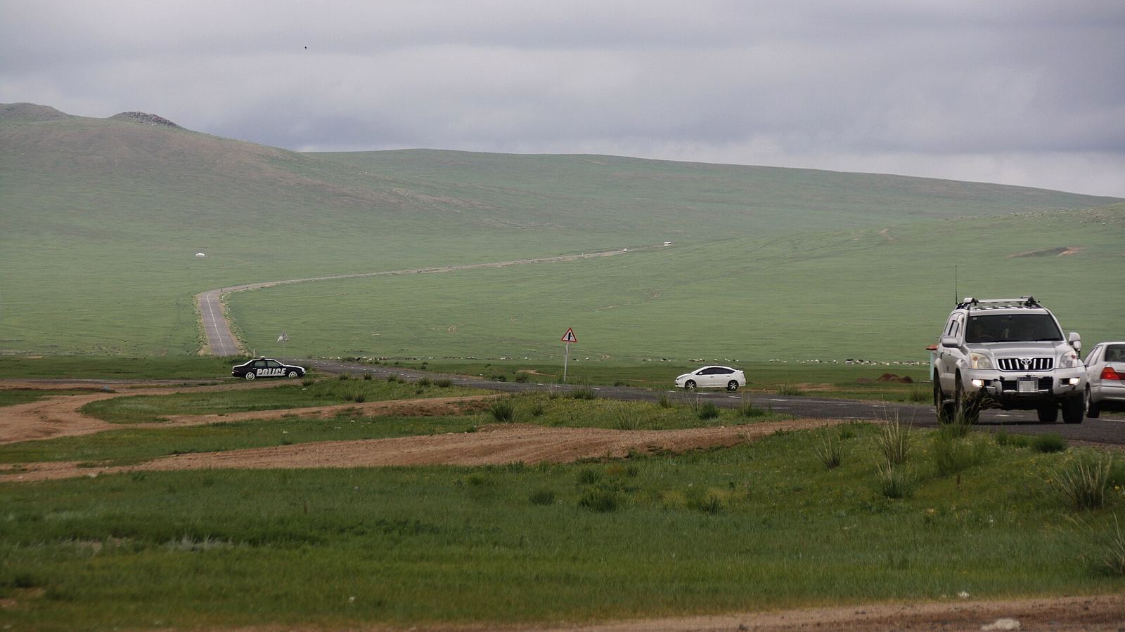 Road scene on the A0501 in the Mongolian steppe with a 4x4 and other cars