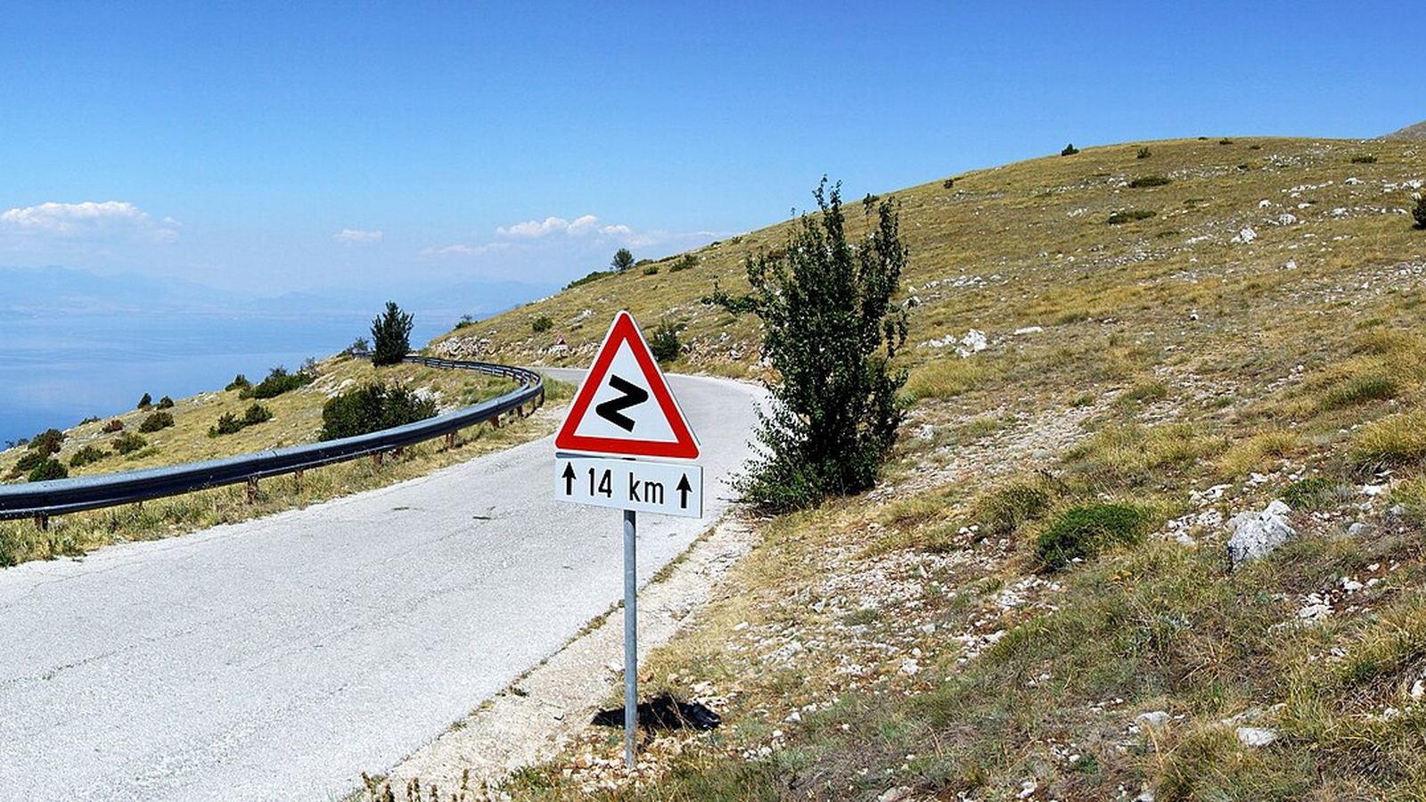 Mountain road with a hairpin warning sign towards the Baba pass in Galicica, above Lake Ohrid