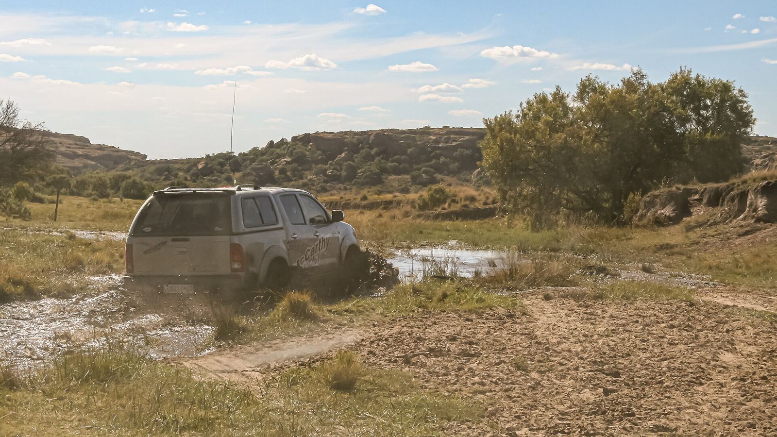 Toyota Hilux 4x4 crossing a muddy stream on a veld track, Korannaberg, Free State, South Africa
