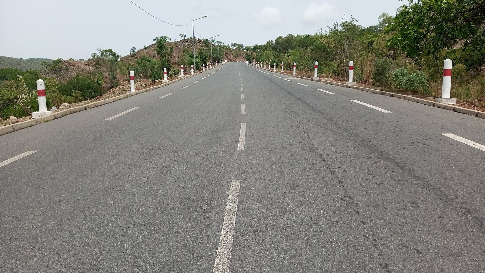 Empty asphalt road with white-and-red bollards between Lassa and Pya, Kara region, Togo