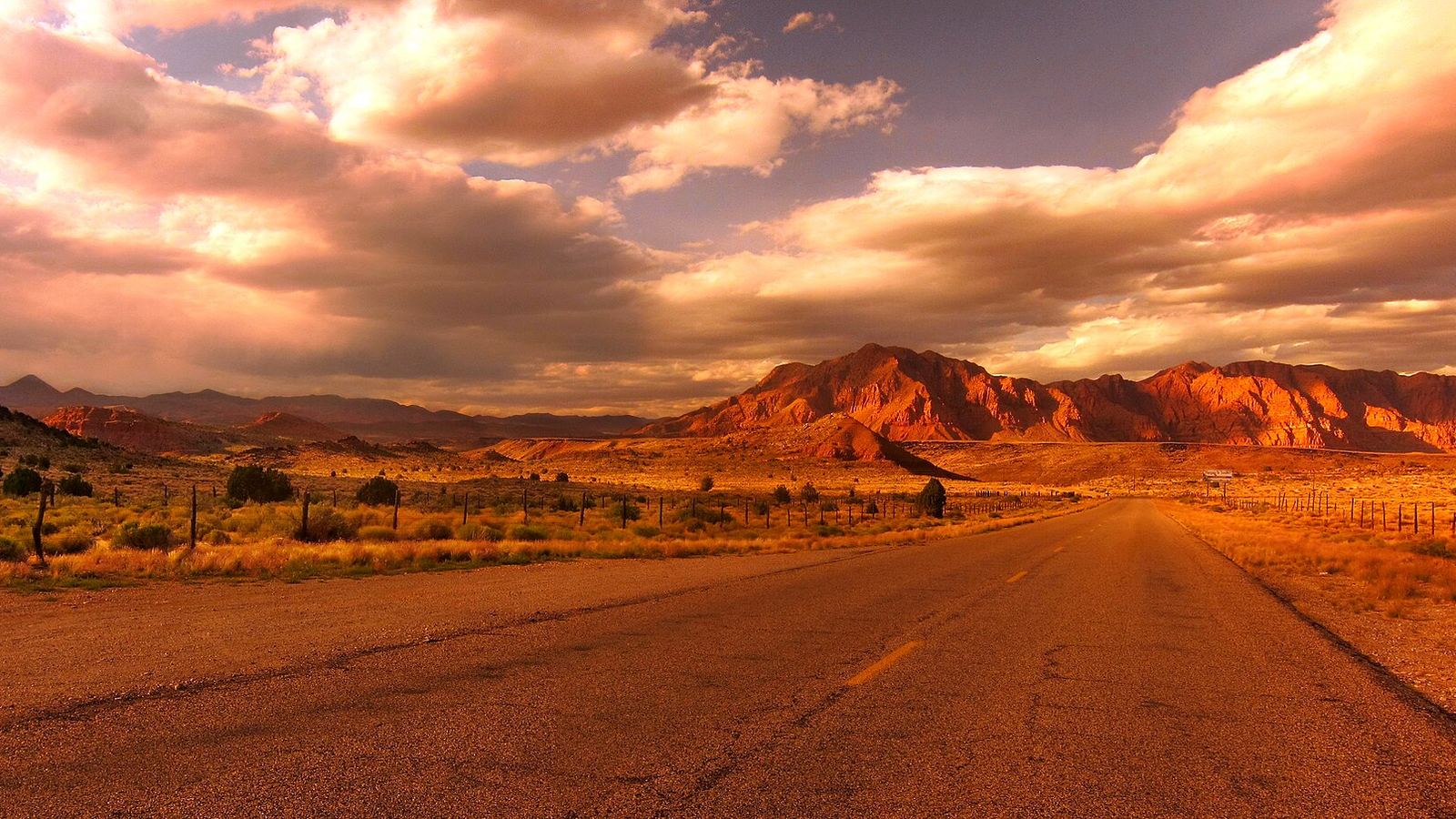 Empty paved road toward red-rock mountains at sunset, American Southwest (exact state not stated), May 2012