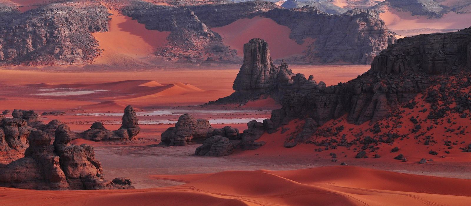 Red dunes and dark rock formations in the Tadrart Rouge